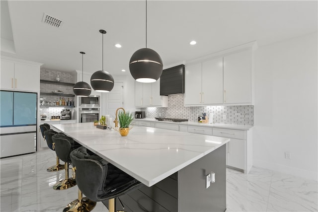 kitchen with white cabinets, pendant lighting, a spacious island, and stainless steel appliances