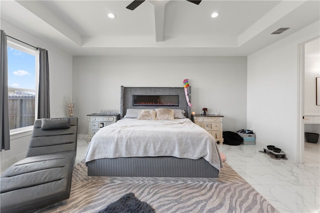 bedroom featuring connected bathroom, a tray ceiling, and ceiling fan