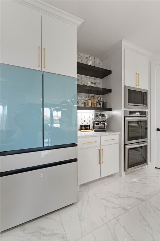 interior space featuring ornamental molding, appliances with stainless steel finishes, and white cabinets