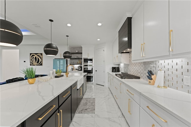 kitchen featuring light stone counters, white cabinetry, appliances with stainless steel finishes, decorative light fixtures, and sink