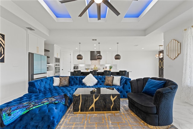 living room featuring ceiling fan and a raised ceiling