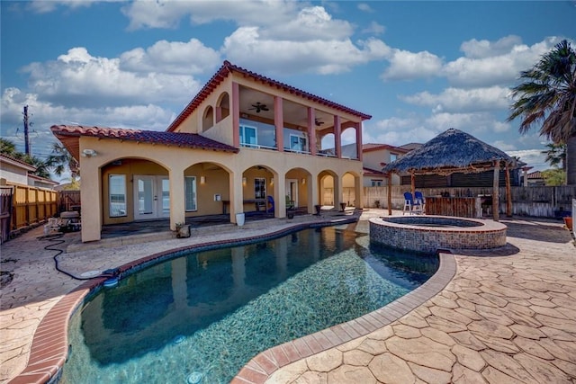 rear view of property with a pool with hot tub, ceiling fan, a gazebo, a balcony, and a patio