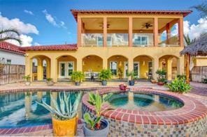 back of house with a patio, an in ground hot tub, fence, a ceiling fan, and a fenced in pool