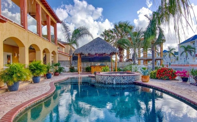 view of swimming pool featuring a patio area, a pool with connected hot tub, fence, and a gazebo