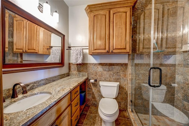 bathroom featuring walk in shower, vanity, tile walls, and toilet