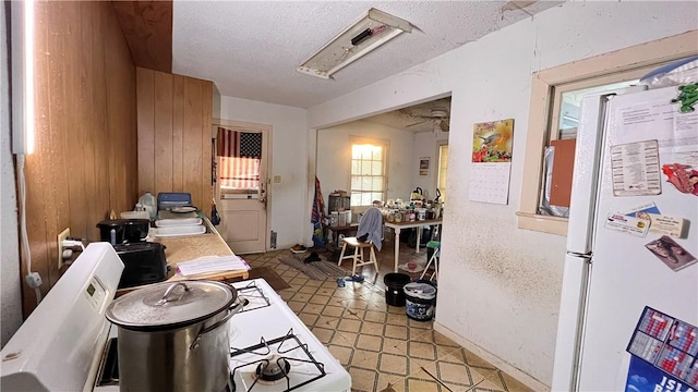 4049 Laguna Shrs, Corpus Christi, TX 78418 - kitchen with freestanding refrigerator, a textured ceiling, wooden walls, and a desk