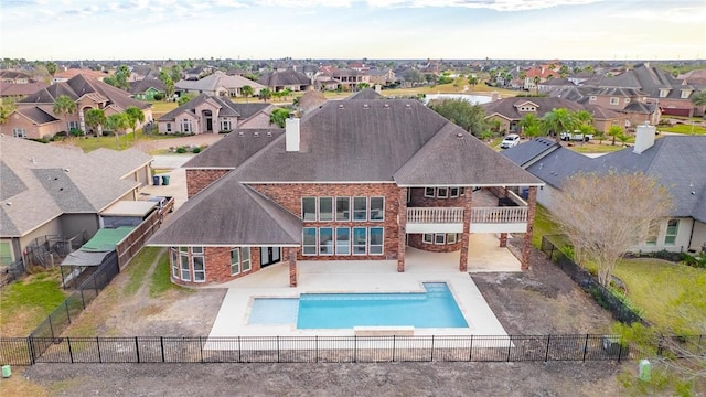 back of house with a patio, a balcony, a fenced backyard, a chimney, and a residential view