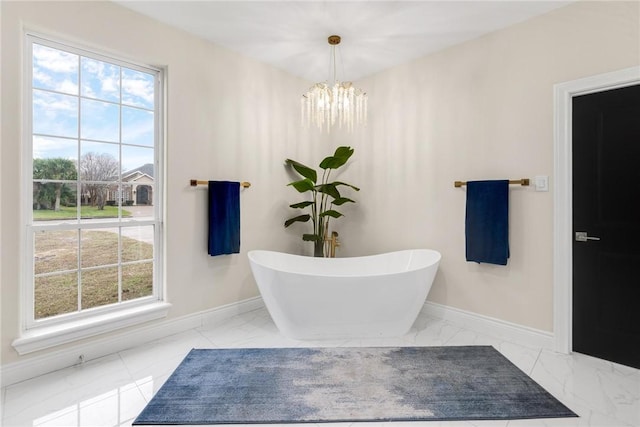 full bath featuring a freestanding tub, baseboards, and marble finish floor