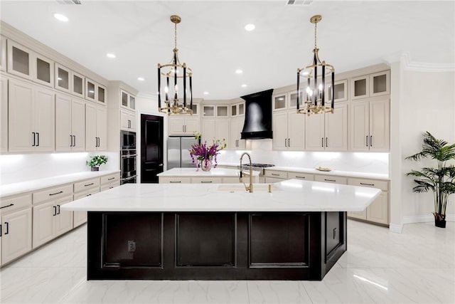 kitchen featuring an inviting chandelier, custom exhaust hood, a large island with sink, stainless steel appliances, and marble finish floor