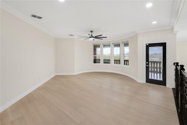 spare room with light wood finished floors, visible vents, baseboards, ornamental molding, and a ceiling fan