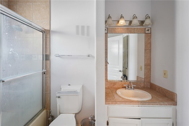 full bathroom featuring toilet, bath / shower combo with glass door, and vanity