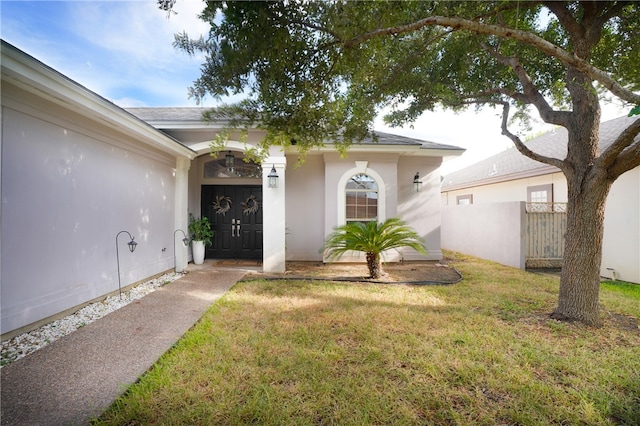 view of exterior entry featuring a lawn