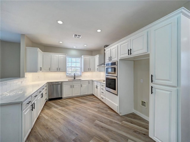 12631 Leopard St, Corpus Christi, TX 78410 - kitchen with appliances with stainless steel finishes, white cabinetry, light wood-style flooring, and recessed lighting