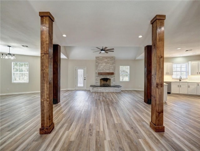 12631 Leopard St, Corpus Christi, TX 78410 - unfurnished living room featuring light wood-style flooring, decorative columns, a stone fireplace, and ceiling fan