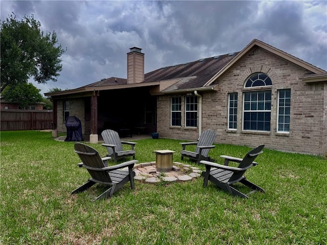 back of property with fence, brick siding, a chimney, a lawn, and a patio