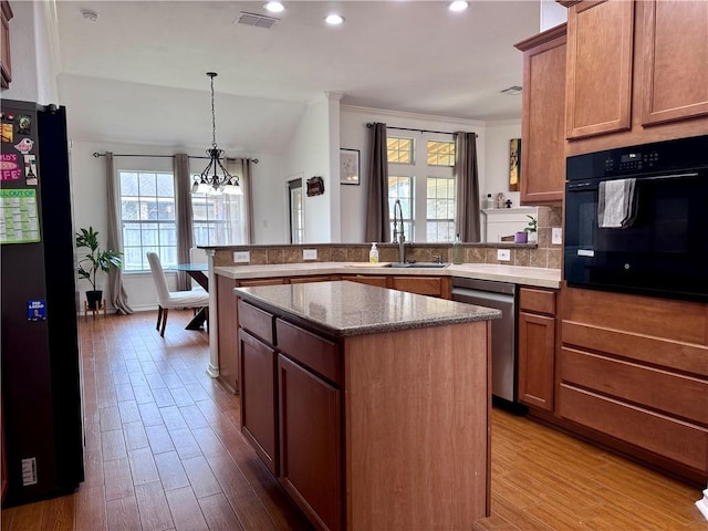 kitchen featuring visible vents, freestanding refrigerator, a peninsula, oven, and a sink