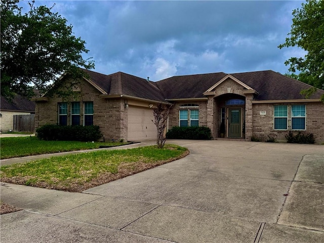 ranch-style home featuring an attached garage, a front yard, driveway, and brick siding