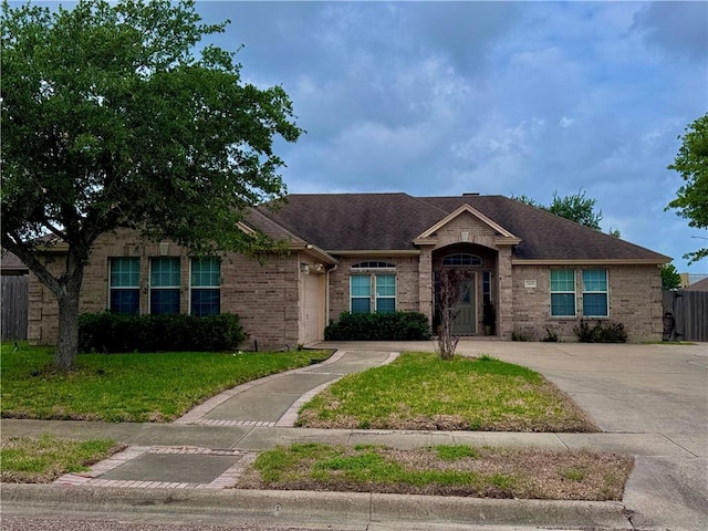single story home with a front lawn, fence, roof with shingles, brick siding, and an attached garage