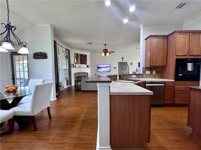 kitchen with a sink, dishwasher, black oven, a tiled fireplace, and visible vents