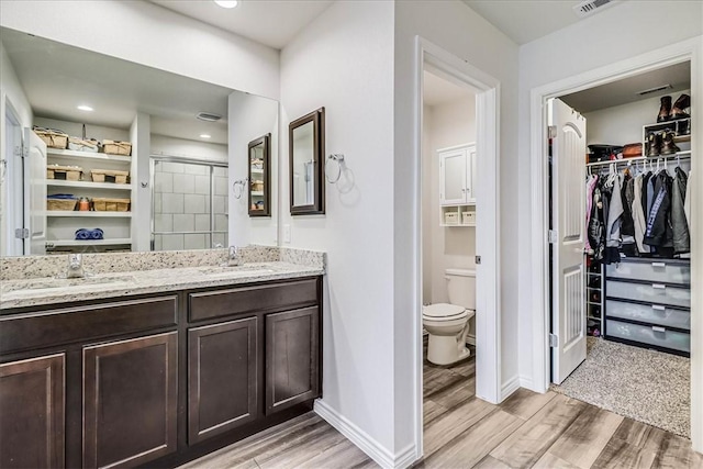 bathroom featuring toilet, a shower with shower door, and vanity