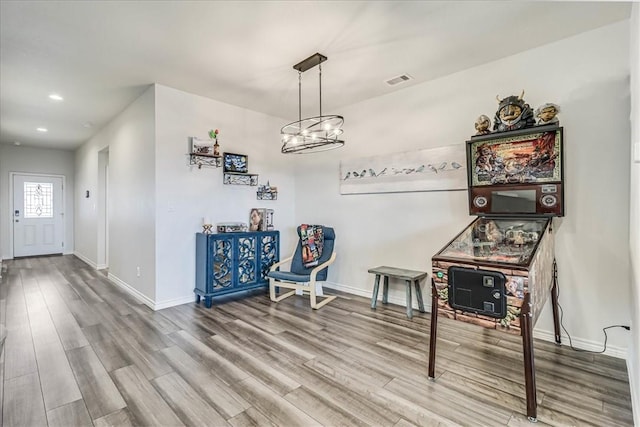 recreation room featuring an inviting chandelier and hardwood / wood-style flooring