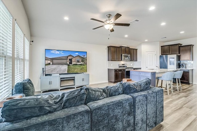 living room featuring ceiling fan, sink, and light hardwood / wood-style floors