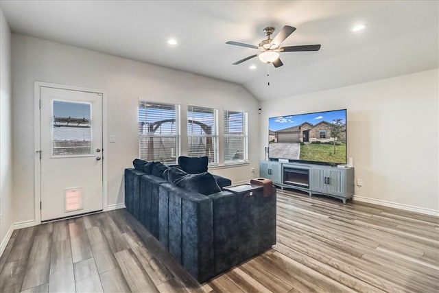 living room with ceiling fan, wood-type flooring, and vaulted ceiling