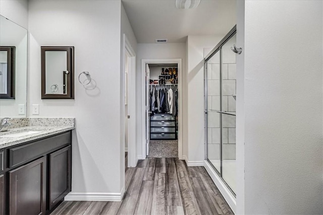 bathroom with a shower with shower door, wood-type flooring, and vanity