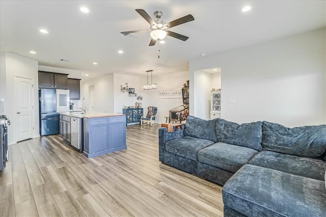 living room featuring ceiling fan, sink, and light hardwood / wood-style floors