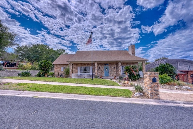 4409 Sue Cir, Corpus Christi, TX 78410 - view of front facade featuring brick siding, a front lawn, covered porch, and a chimney