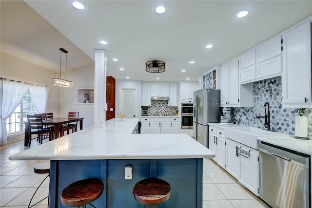 4409 Sue Cir, Corpus Christi, TX 78410 - kitchen featuring light tile patterned floors, a kitchen breakfast bar, tasteful backsplash, a sink, and stainless steel appliances