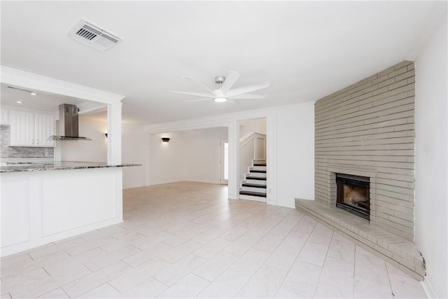 4925 Valley Stream Dr, Corpus Christi, TX 78413 - unfurnished living room featuring a ceiling fan, a brick fireplace, and stairway