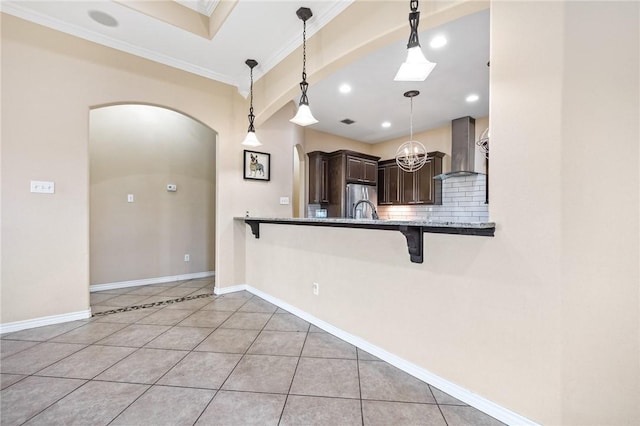 3813 Elvis Dr, Corpus Christi, TX 78414 - kitchen featuring wall chimney exhaust hood, freestanding refrigerator, arched walkways, a breakfast bar, and dark brown cabinetry