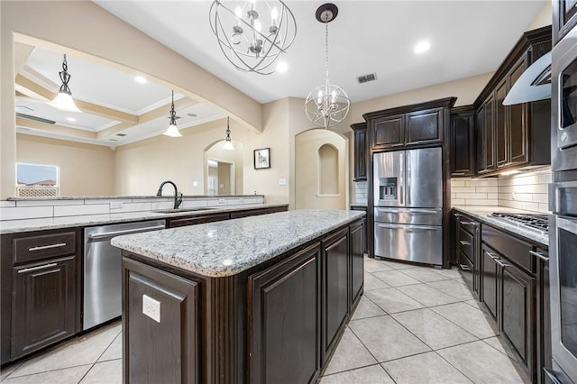3813 Elvis Dr, Corpus Christi, TX 78414 - kitchen featuring appliances with stainless steel finishes, arched walkways, a chandelier, a center island, and ornamental molding