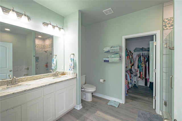 bathroom with wood-type flooring, vanity, toilet, and an enclosed shower