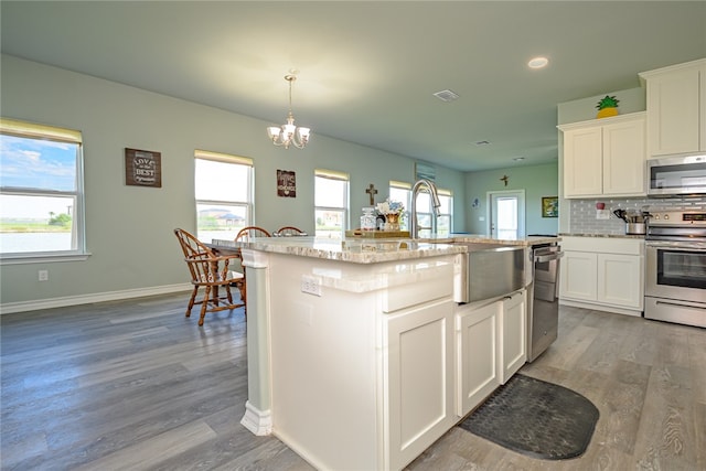 kitchen featuring white cabinetry, appliances with stainless steel finishes, an island with sink, and light hardwood / wood-style flooring