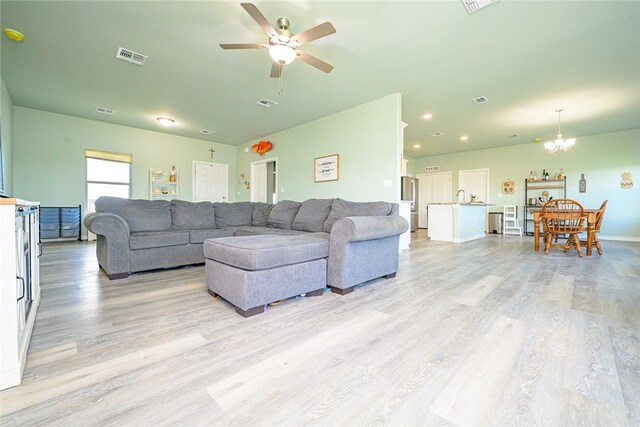 living room with sink, light hardwood / wood-style floors, and ceiling fan with notable chandelier