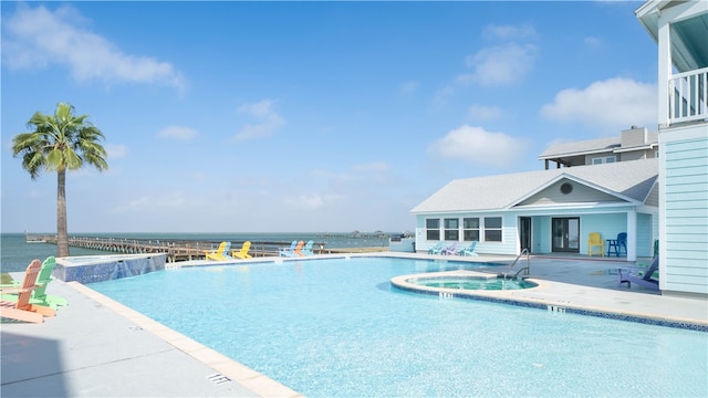 view of pool with a community hot tub, a patio, a water view, and pool water feature