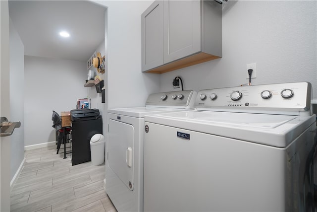 washroom with cabinets, washing machine and clothes dryer, and light hardwood / wood-style floors