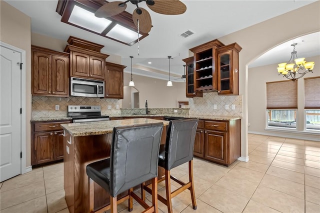 7406 Brush Creek Dr, Corpus Christi, TX 78414 - kitchen with stainless steel appliances, a chandelier, glass insert cabinets, light tile patterned floors, and tasteful backsplash