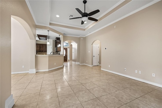7406 Brush Creek Dr, Corpus Christi, TX 78414 - unfurnished living room featuring arched walkways, a tray ceiling, a ceiling fan, ornamental molding, and light tile patterned flooring