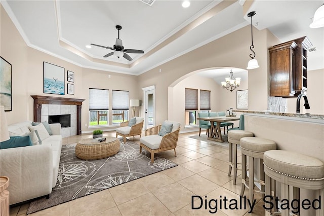7406 Brush Creek Dr, Corpus Christi, TX 78414 - living room featuring ornamental molding, arched walkways, a chandelier, a ceiling fan, and a tile fireplace