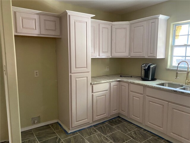 kitchen featuring white cabinets, sink, and light stone countertops