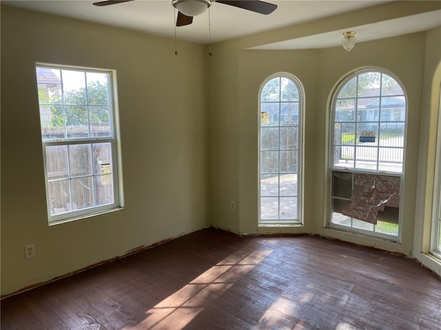 empty room with ceiling fan, dark hardwood / wood-style floors, and plenty of natural light