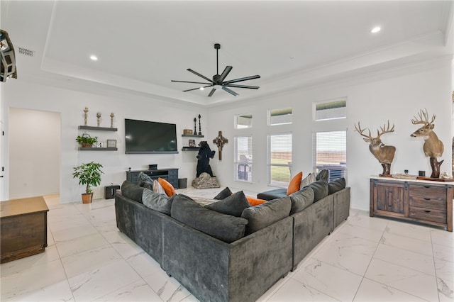 living room with ornamental molding, a tray ceiling, and ceiling fan