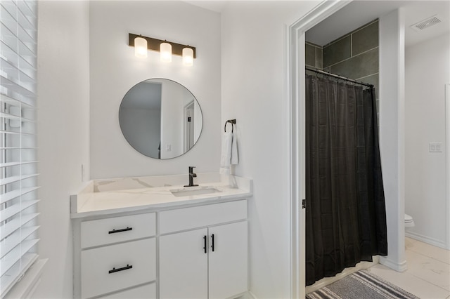 bathroom with toilet, vanity, and walk in shower