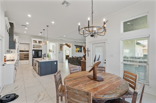 dining area with ornamental molding, sink, and an inviting chandelier