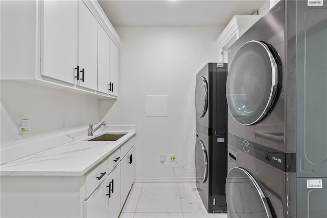 laundry area with stacked washer and clothes dryer, cabinets, and sink