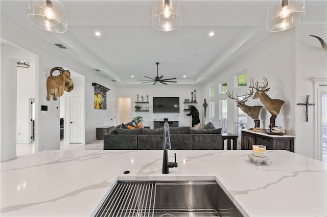 kitchen with pendant lighting, sink, and light stone countertops