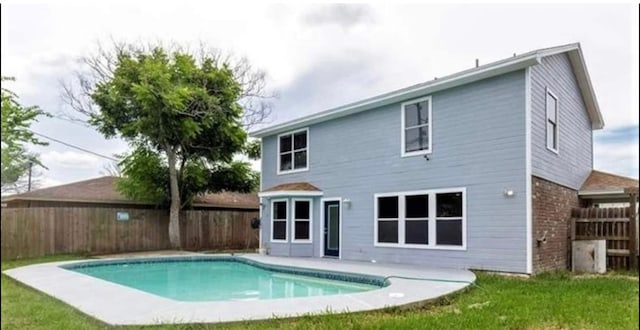 rear view of property featuring a fenced in pool